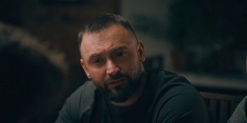 Movie still from “Superpower” (2023), directed by Aaron Kaufman – A person wearing a black shirt; Close Up shot, Over the shoulder angle