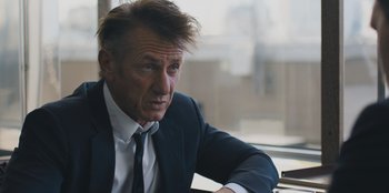 Movie still from “Superpower” (2023), directed by Aaron Kaufman – A person wearing a suit and tie; Close Up shot, Over the shoulder angle