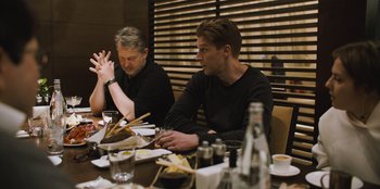 Movie still from “Superpower” (2023), directed by Aaron Kaufman – Two men sitting at a table with plates and chopsticks; Medium shot, Over the shoulder angle
