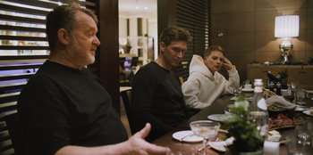 Movie still from “Superpower” (2023), directed by Aaron Kaufman – A group of people sitting around a table; Medium shot, Over the shoulder angle