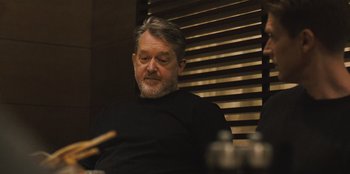 Movie still from “Superpower” (2023), directed by Aaron Kaufman – A man sitting in front of a window; Close Up shot, Over the shoulder angle