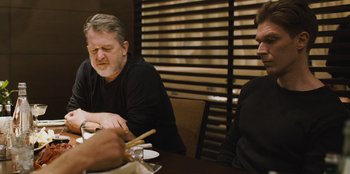Movie still from “Superpower” (2023), directed by Aaron Kaufman – Two people sitting at a table with chopsticks; Medium shot, Over the shoulder angle