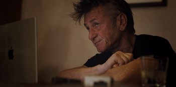 Movie still from “Superpower” (2023), directed by Aaron Kaufman – A person sitting at a table; Close Up shot, Low angle