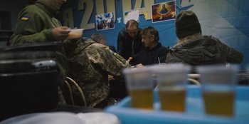Movie still from “Superpower” (2023), directed by Aaron Kaufman – A group of people sitting at a table with drinks; Medium shot, Over the shoulder angle