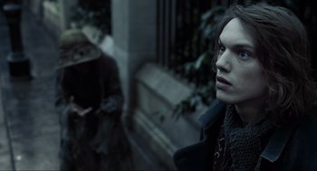 Movie still from “Sweeney Todd: The Demon Barber of Fleet Street” (2007), directed by Tim Burton – A young man is standing in front of a building; Close Up shot, Over the shoulder angle