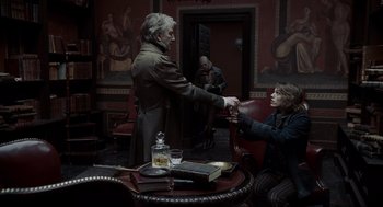 Movie still from “Sweeney Todd: The Demon Barber of Fleet Street” (2007), directed by Tim Burton – A man and a woman sitting at a table in front of a painting; Medium shot, Over the shoulder angle