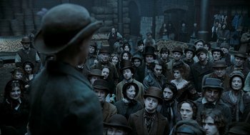 Movie still from “Sweeney Todd: The Demon Barber of Fleet Street” (2007), directed by Tim Burton – A group of people gathered together in a dark place; Wide shot, High angle