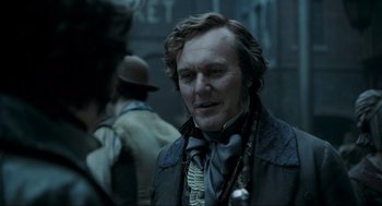 Movie still from “Sweeney Todd: The Demon Barber of Fleet Street” (2007), directed by Tim Burton – A person wearing a suit and tie; Close Up shot, Over the shoulder angle