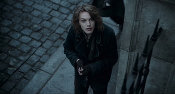 Movie still from “Sweeney Todd: The Demon Barber of Fleet Street” (2007), directed by Tim Burton – A woman in a black coat holding a knife; Medium shot, High angle