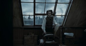 Movie still from “Sweeney Todd: The Demon Barber of Fleet Street” (2007), directed by Tim Burton – A man standing in front of a large window with smoke billowing out of the windows; Medium shot, Low angle