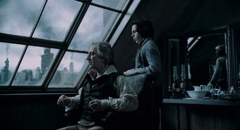 Movie still from “Sweeney Todd: The Demon Barber of Fleet Street” (2007), directed by Tim Burton – A man and a woman sitting next to each other in front of a window; Medium shot, Low angle
