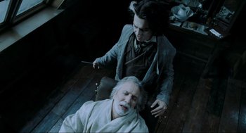 Movie still from “Sweeney Todd: The Demon Barber of Fleet Street” (2007), directed by Tim Burton – An old man is lying on the floor while a young man is holding a knife; Medium shot, High angle