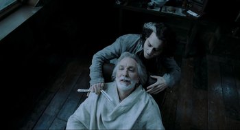 Movie still from “Sweeney Todd: The Demon Barber of Fleet Street” (2007), directed by Tim Burton – An older man being shaved by a younger man; Medium shot, Overhead angle