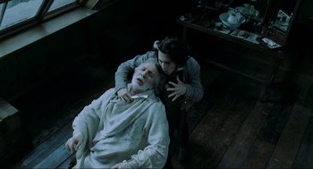 Movie still from “Sweeney Todd: The Demon Barber of Fleet Street” (2007), directed by Tim Burton – An older man laying on the floor next to a young woman; Medium shot, Overhead angle