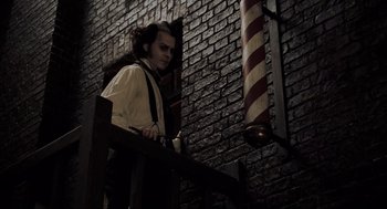 Movie still from “Sweeney Todd: The Demon Barber of Fleet Street” (2007), directed by Tim Burton – A man standing in front of a brick wall; Medium shot, Low angle
