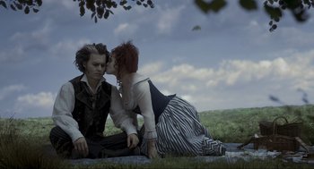 Movie still from “Sweeney Todd: The Demon Barber of Fleet Street” (2007), directed by Tim Burton – A man and a woman sitting on the ground kissing; Medium shot, High angle
