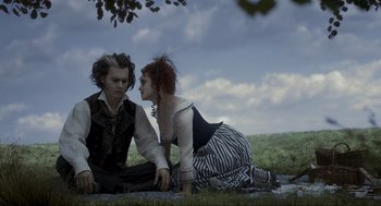 Movie still from “Sweeney Todd: The Demon Barber of Fleet Street” (2007), directed by Tim Burton – A man and a woman sitting on the ground in a field; Medium shot, High angle