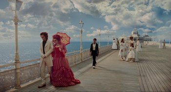 Movie still from “Sweeney Todd: The Demon Barber of Fleet Street” (2007), directed by Tim Burton – A group of people walking on a pier near the ocean; Wide shot, High angle