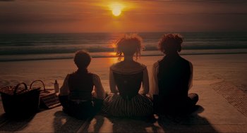 Movie still from “Sweeney Todd: The Demon Barber of Fleet Street” (2007), directed by Tim Burton – A group of people sitting on the beach watching the sun go down; Wide shot, High angle
