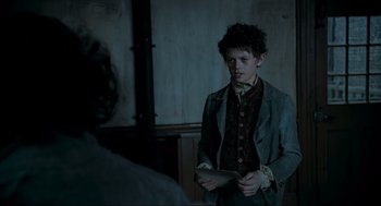 Movie still from “Sweeney Todd: The Demon Barber of Fleet Street” (2007), directed by Tim Burton – A man in a suit and tie holding a paper; Medium shot, Over the shoulder angle