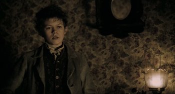Movie still from “Sweeney Todd: The Demon Barber of Fleet Street” (2007), directed by Tim Burton – A young man in a suit and tie in front of a wall clock; Medium shot, Low angle
