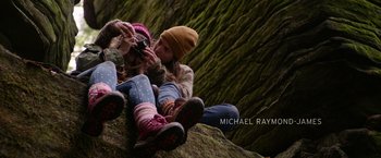 Movie still from “Sweet Girl” (2021), directed by Brian Andrew Mendoza – Two young people sitting on a rock taking a picture; Wide shot, Overhead angle