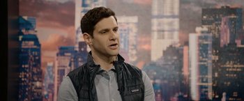 Movie still from “Sweet Girl” (2021), directed by Brian Andrew Mendoza – A man in a black vest is talking to the camera; Medium shot, Over the shoulder angle