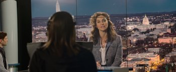 Movie still from “Sweet Girl” (2021), directed by Brian Andrew Mendoza – A woman sitting in front of a television screen; Medium shot, Over the shoulder angle
