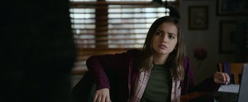 Movie still from “Sweet Girl” (2021), directed by Brian Andrew Mendoza – A young woman sitting in a chair in front of a window; Medium shot, Over the shoulder angle