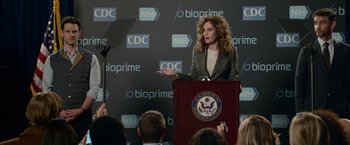 Movie still from “Sweet Girl” (2021), directed by Brian Andrew Mendoza – A woman standing in front of a podium speaking; Medium shot, Over the shoulder angle