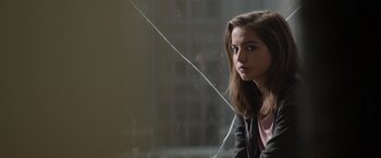 Movie still from “Sweet Girl” (2021), directed by Brian Andrew Mendoza – A young woman sitting in front of a glass window; Close Up shot, Over the shoulder angle