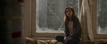 Movie still from “Sweet Girl” (2021), directed by Brian Andrew Mendoza – A woman sitting in front of an open window; Medium shot, High angle