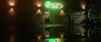 Movie still from “Sweet Girl” (2021), directed by Brian Andrew Mendoza – A neon sign is lit up in the dark; Extreme Wide shot, High angle