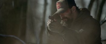 Movie still from “Sweet Girl” (2021), directed by Brian Andrew Mendoza – A man holding a gun while wearing a hat; Close Up shot, Over the shoulder angle