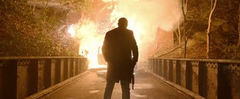 Movie still from “Sweet Girl” (2021), directed by Brian Andrew Mendoza – A man standing in front of an exploding car; Wide shot, Low angle