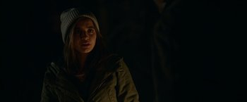 Movie still from “Sweet Girl” (2021), directed by Brian Andrew Mendoza – A woman wearing a jacket and a hat in the dark; Close Up shot, Over the shoulder angle