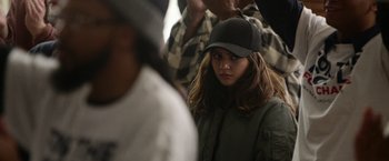 Movie still from “Sweet Girl” (2021), directed by Brian Andrew Mendoza – A woman wearing a baseball cap and a jacket; Close Up shot, Over the shoulder angle