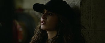 Movie still from “Sweet Girl” (2021), directed by Brian Andrew Mendoza – A woman wearing a black baseball cap and a black jacket; Close Up shot, Over the shoulder angle