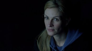 Movie still from “Closer” (2004), directed by Mike Nichols – A woman is looking at the camera with a dark background; Close Up shot, Over the shoulder angle