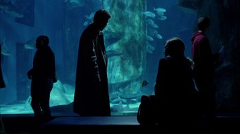 Movie still from “Closer” (2004), directed by Mike Nichols – Two people in a dark room looking at a fish tank; Wide shot, Over the shoulder angle