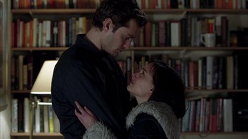 Movie still from “Closer” (2004), directed by Mike Nichols – A man and a woman embracing in front of a bookshelf; Medium shot, Low angle