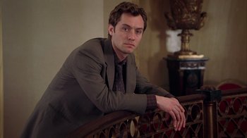 Movie still from “Closer” (2004), directed by Mike Nichols – A man in a suit leaning on a railing; Medium shot, Low angle