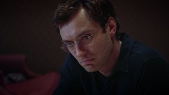 Movie still from “Closer” (2004), directed by Mike Nichols – A person wearing glasses and a black shirt; Close Up shot, Low angle