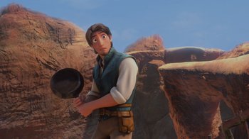 Movie still from “Tangled” (2010), directed by Byron Howard – A man holding a frying pan standing in front of a mountain; Medium shot, Over the shoulder angle