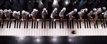 Movie still from “Ted 2” (2015), directed by Seth MacFarlane – A group of people standing on top of a piano; Extreme Wide shot, Overhead angle