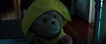Movie still from “Ted 2” (2015), directed by Seth MacFarlane – A brown teddy bear wearing a yellow raincoat and holding a plastic cup; Close Up shot, Low angle
