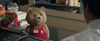 Movie still from “Ted 2” (2015), directed by Seth MacFarlane – A teddy bear is wearing a red apron; Medium shot, Over the shoulder angle