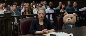 Movie still from “Ted 2” (2015), directed by Seth MacFarlane – A woman sitting at a table in front of a group of people; Medium shot, High angle