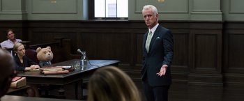 Movie still from “Ted 2” (2015), directed by Seth MacFarlane – A man standing in front of a table in a courtroom; Medium shot, Over the shoulder angle