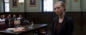 Movie still from “Ted 2” (2015), directed by Seth MacFarlane – A woman sitting in front of a table in a courtroom; Medium shot, Over the shoulder angle